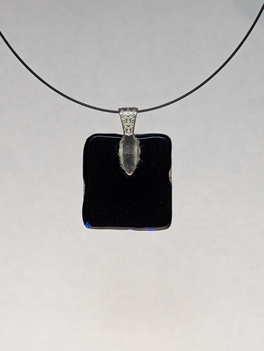The black back of a blue dichroic fused glass pendant with a silver metallic clasp, displayed on a black stainless steel necklace.