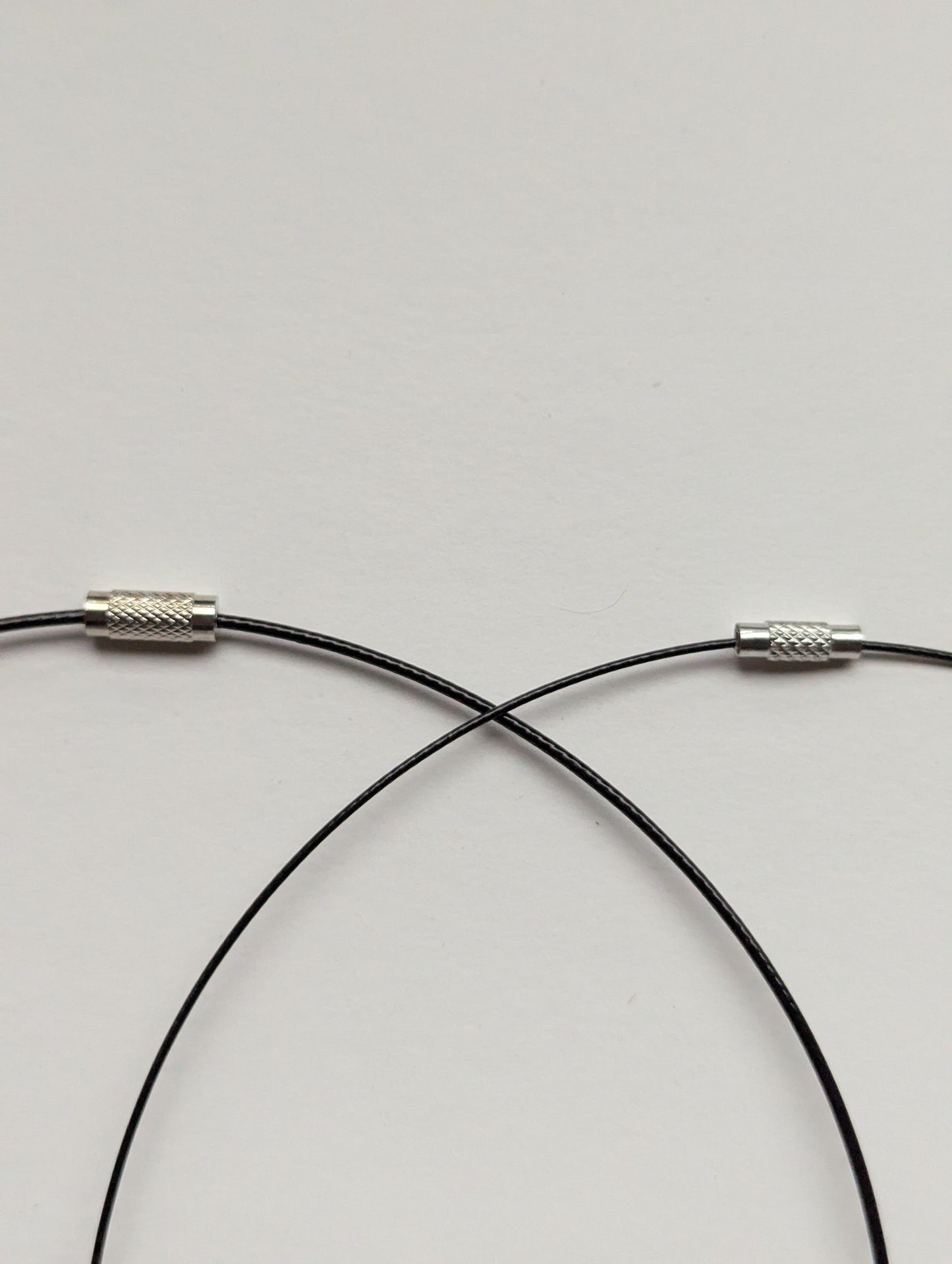 A side-by-side comparison of thick and thin black stainless steel necklaces.