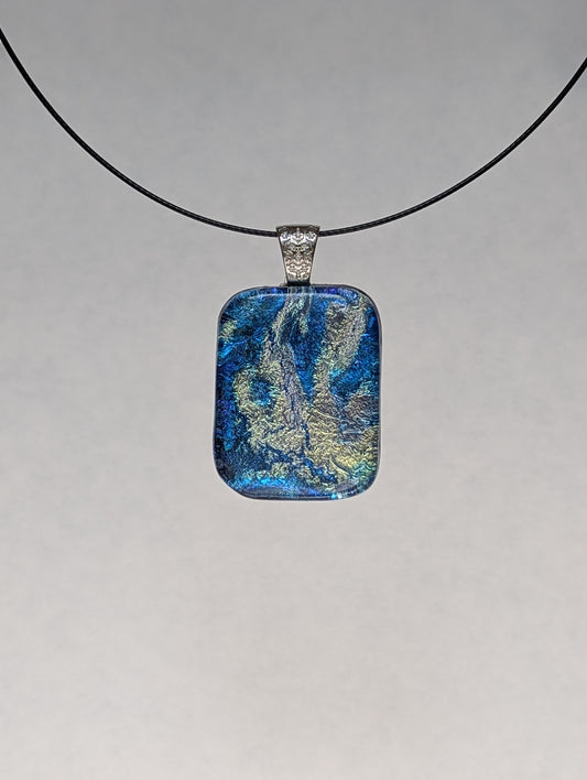 A blue and silver iridescent fused glass pendant with a metallic clasp, displayed on a black stainless steel necklace against a white background.