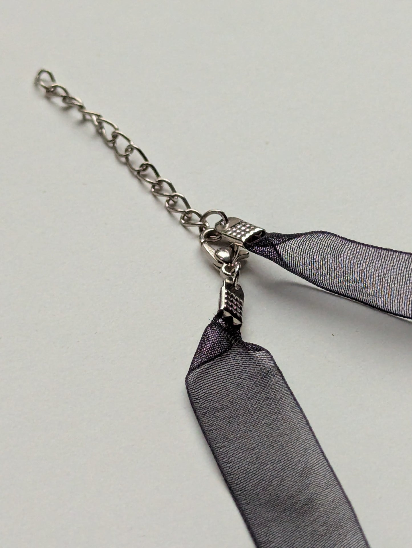 close up of ribbon necklace and silver metallic clasp with adjustable chain