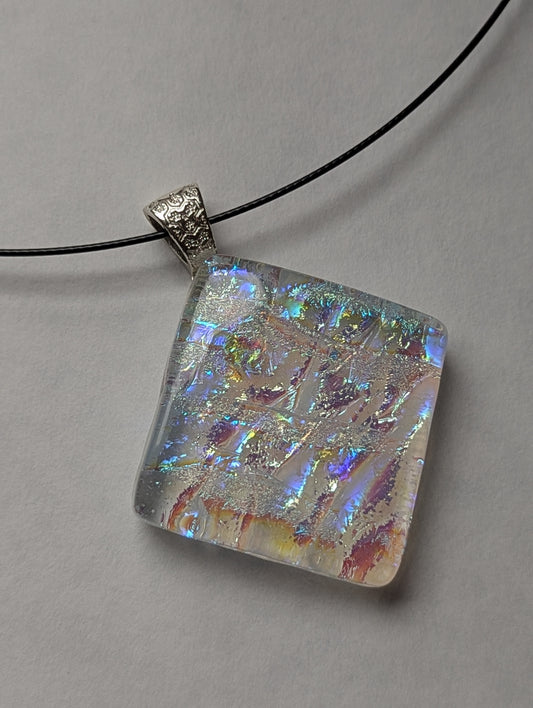A colorful clear iridescent fused glass pendant with a metallic clasp, displayed on a black stainless steel necklace against a white background.