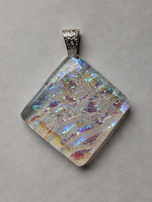 A colorful clear iridescent fused glass pendant with a metallic clasp, displayed against a white background.