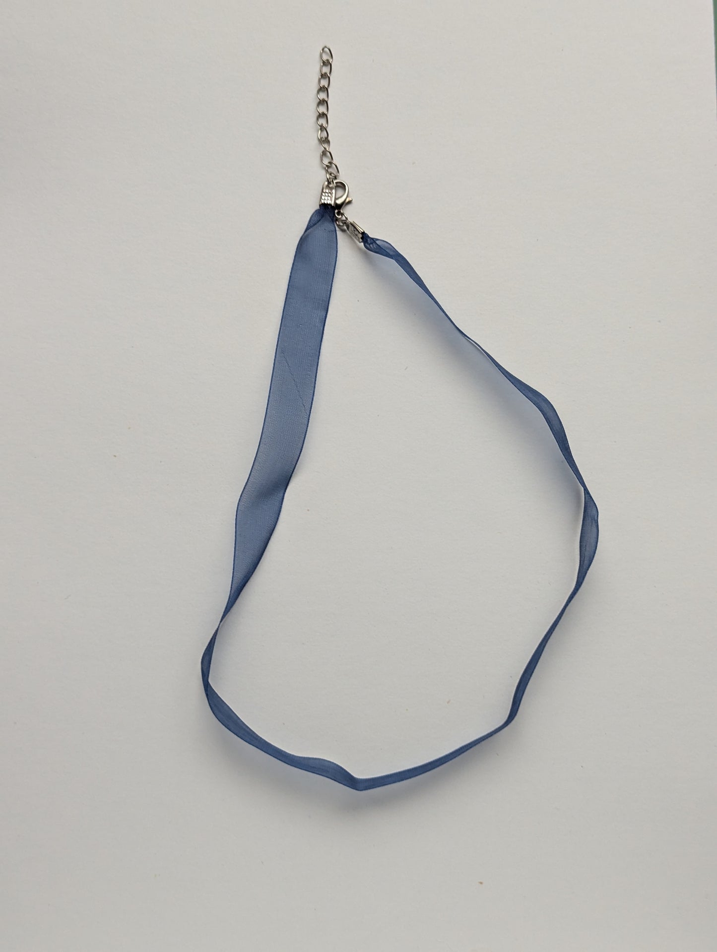 blue ribbon necklace on a neutral background