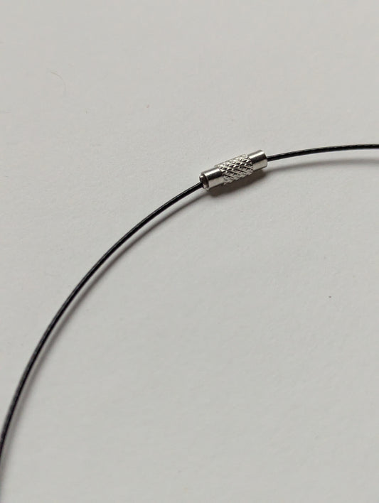 Close-up of a black stainless steel necklace with a screw clasp on a plain background.