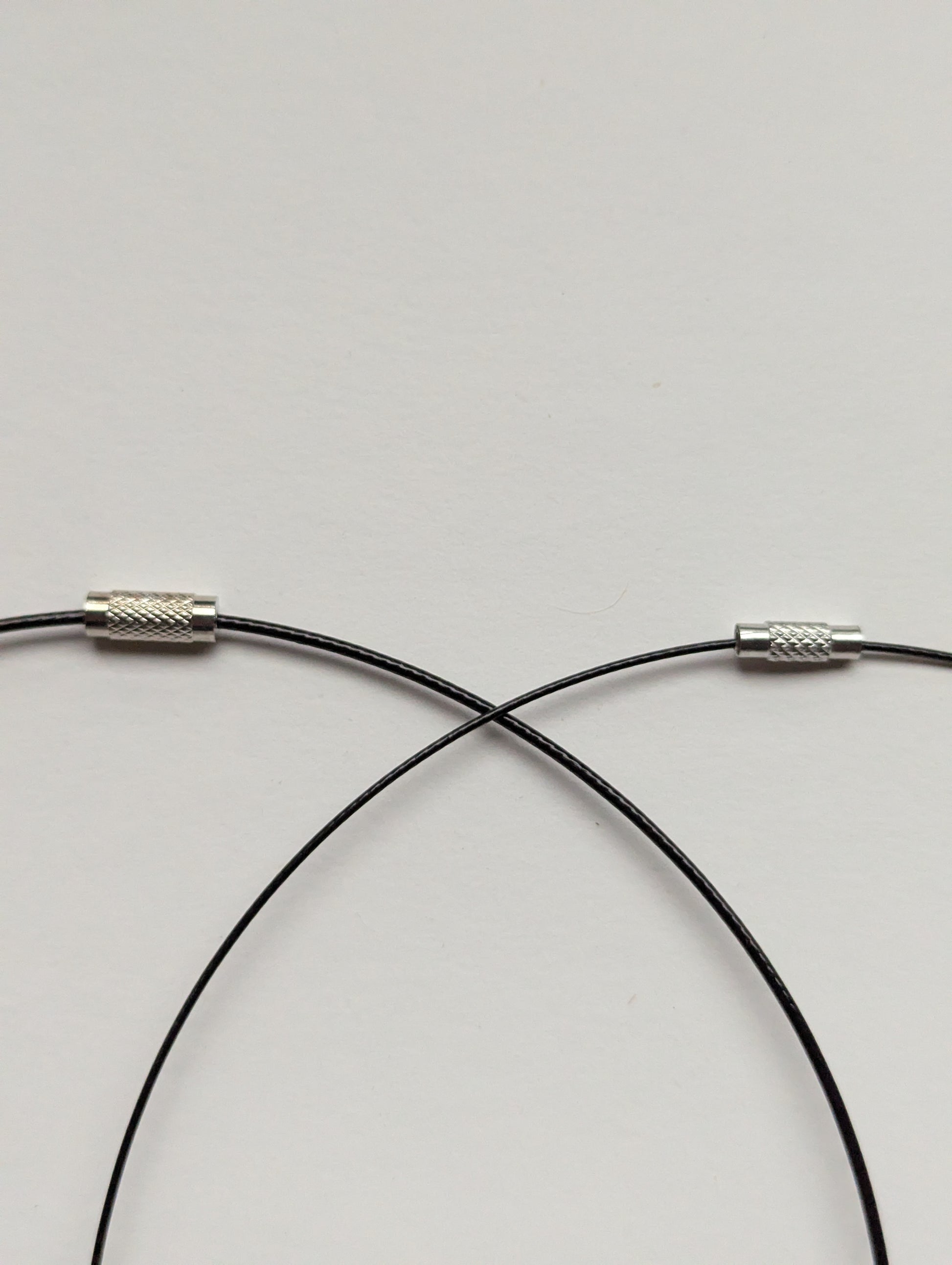 A side-by-side comparison of thick and thin black stainless steel necklaces.