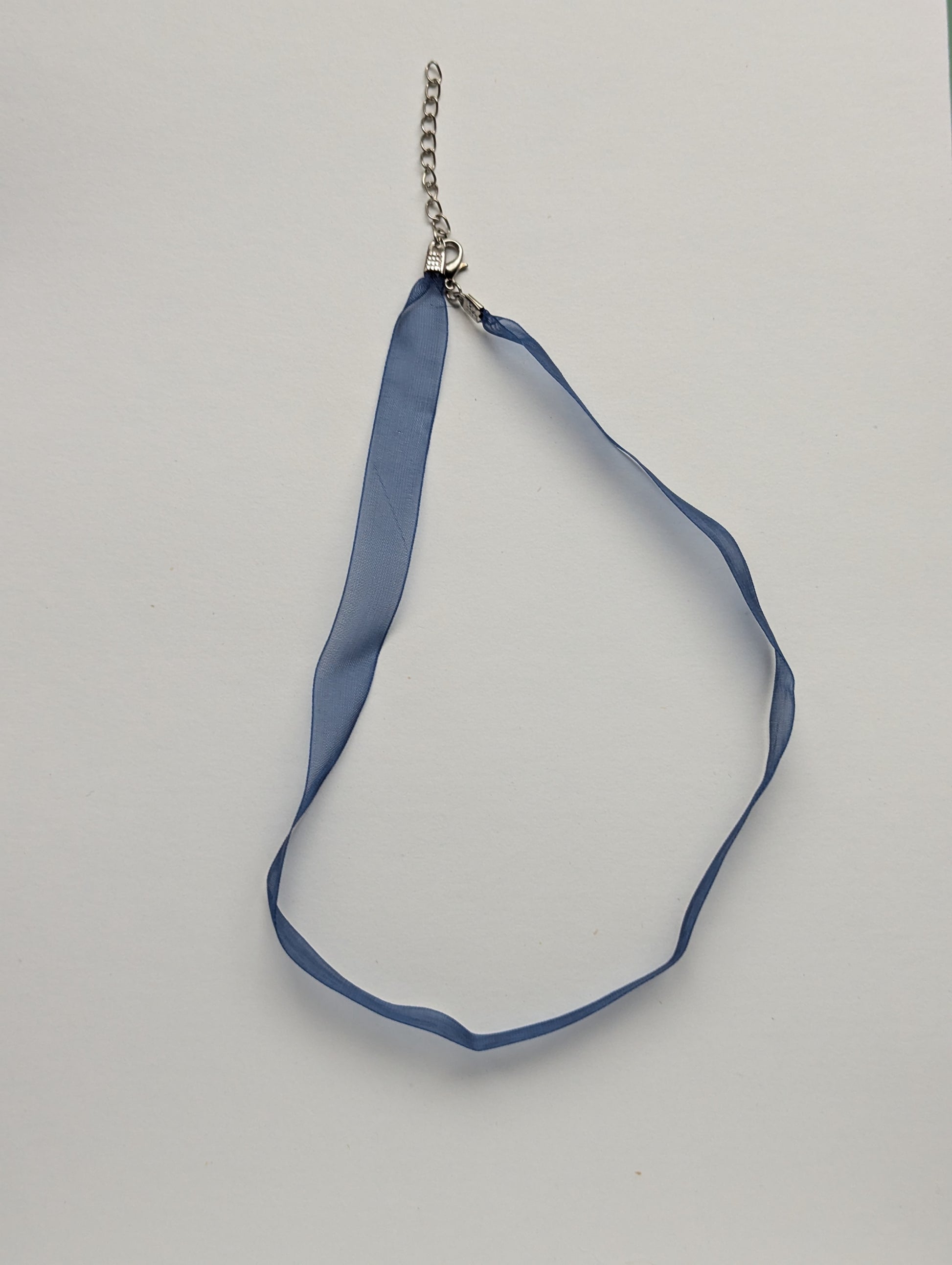 blue ribbon necklace on a neutral background 