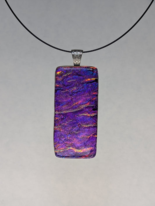 A rectangular fused glass pendant with a silver metallic clasp on a black stainless steel necklace. 